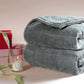 Cozy gray sherpa weighted blanket stacked next to a candle and gift box, perfect for warmth and relaxation.